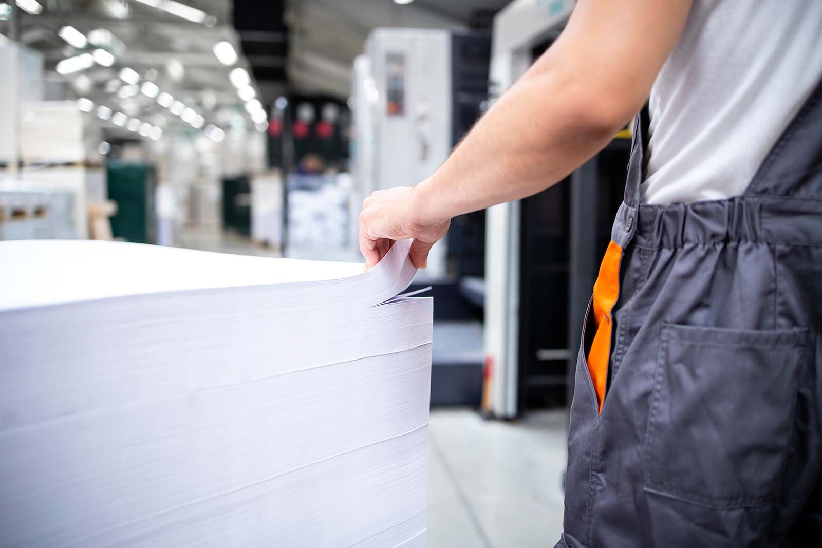 A factory assistant is holding a stack of paper.