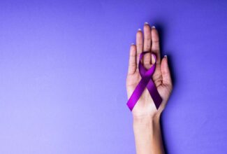 A woman's hand holding a purple ribbon representing pancreatic cancer on a purple background.